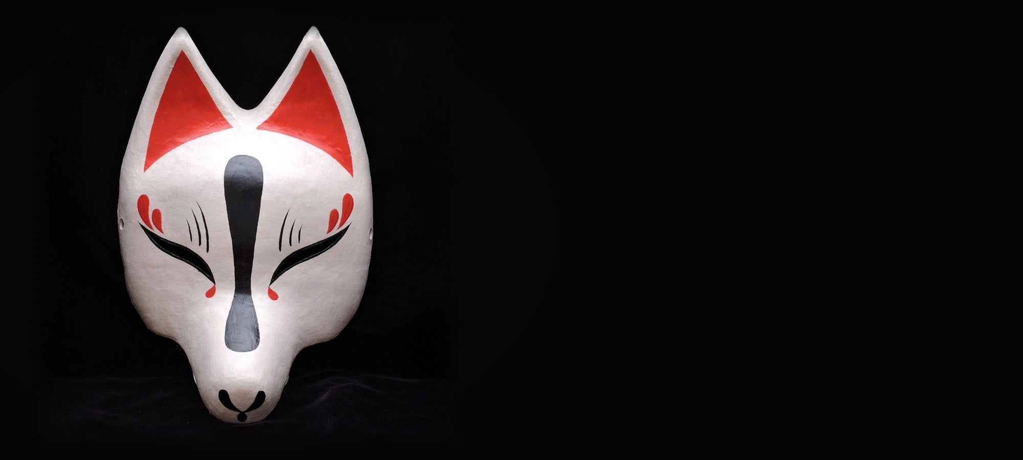 Shirayoi mask against black cloth, lit from the front