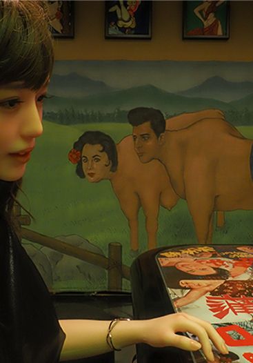 A hyper-real doll, face to face across a table
